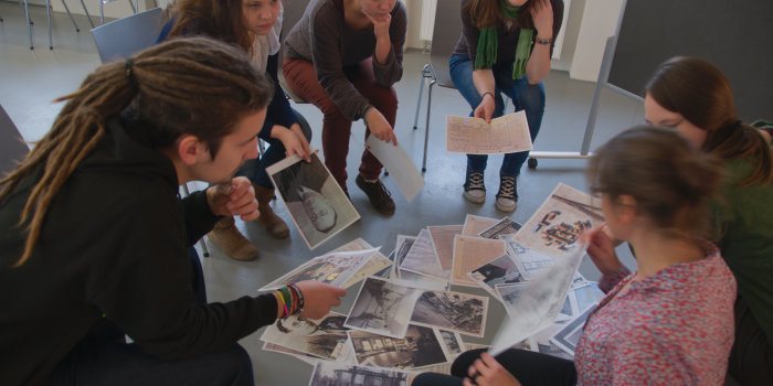 A group of people gathering around a pile of pictures. The pictures are of historical documents.