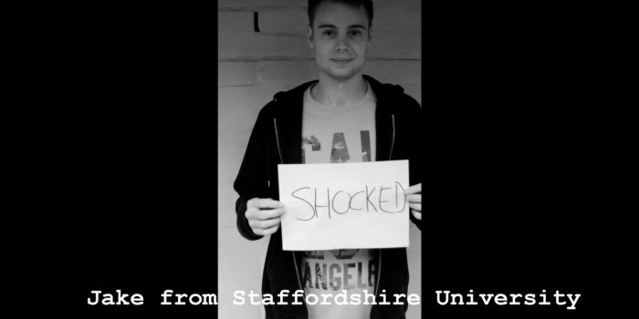 Junger Mann hält Schild mit Aufschrift "Shocked"