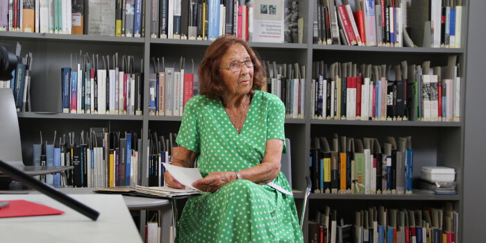 Frau mit grünem Kleid vor Bücherwand
