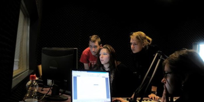 Vier Personen arbeiten in einem Tonstudio. 