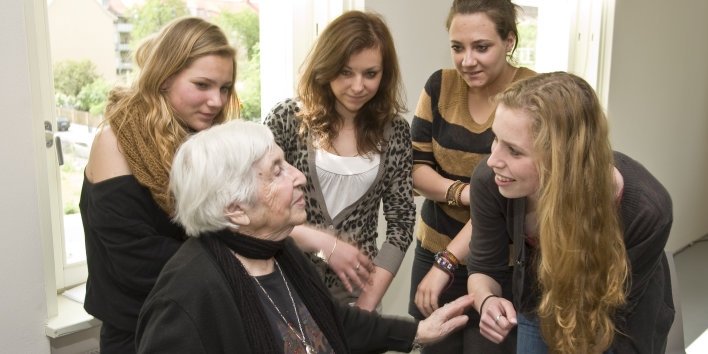 Vier junge Frauen im Gespräch mit einer alten Dame