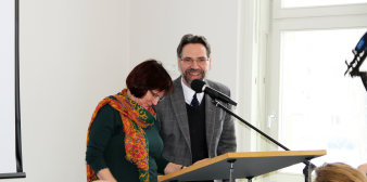 Mann und Frau stehen hinter Rednerpult am Mikrofon