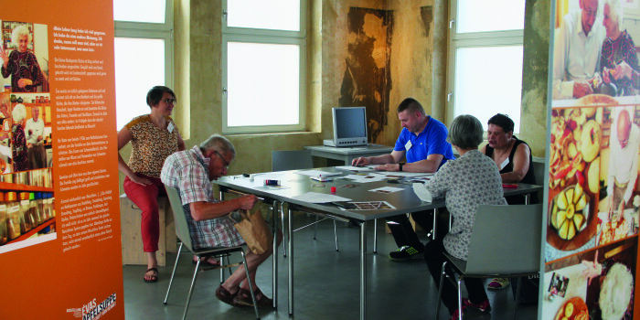 Farbfoto. Vier Menschen sitzen an einem Tisch.