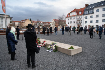 Menschen gedenken am Stein der Erinnerung.